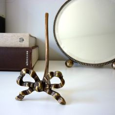 a metal object sitting on top of a white table next to a mirror and book