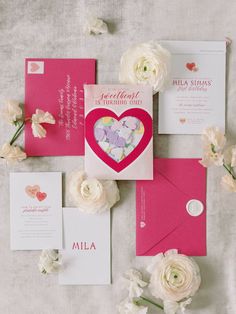 the wedding stationery is laid out on top of the table with flowers and cards