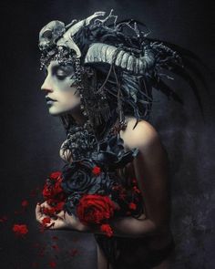 a woman with black and red flowers in her hair is wearing a mask that has feathers on it