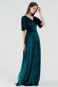 a woman in a long green dress is looking down at her head and she's wearing