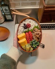 a person holding a bowl of food on top of a counter