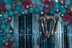 the balloon arch is decorated with blue, silver and pink balloons that spell out v