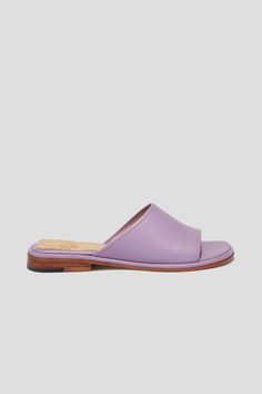 Get ready for the Pileta Slide in Lilac to be your favorite summer shoe. It's got the ease of a flip-flop but is as finely crafted as any shoe in our collection, which means it's going to be a keeper. Its simple shape and stand-out color will make it easy to combine with a range of textures, fabrications and silhouettes in your summer wardrobe. Who it's for: The woman who loves a pop of color. Kidskin upper with vegetable tanned leather lining and a 25 mm stacked leather heel and sole. Handmade in Argentina. Classic Summer Slippers With Rubber Sole, Classic Flat Slippers For Summer, Classic Summer Slippers With Textured Footbed, Summer Classic Closed Toe Slippers, Classic Closed Toe Summer Slippers, Classic Beach Slides With Rubber Sole, Summer Slides With Stitched Sole And Open Toe, Summer Open Toe Slides With Stitched Sole, Classic Summer Slippers With Round Toe