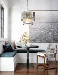 a dining room with a bench, table and chair next to a painting on the wall