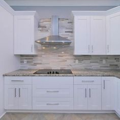 a kitchen with white cabinets and marble counter tops