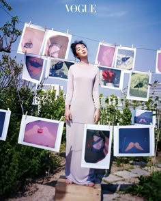 a woman standing in front of pictures hanging on a clothes line with her eyes closed