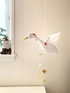 a white swan mobile hanging from the ceiling next to a window with star decorations on it