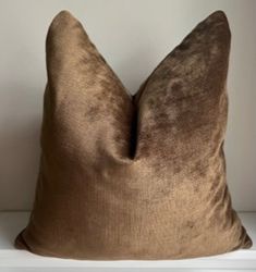 a brown pillow sitting on top of a white shelf