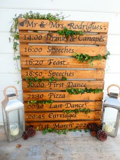 a wooden sign that has some plants growing on it and two lanterns next to it