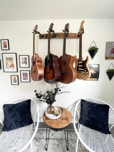 two chairs and a table with guitars hanging on the wall