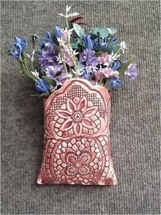 a vase filled with purple flowers sitting on top of a carpeted floor next to a wall