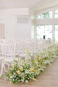 rows of white chairs with yellow and white flowers