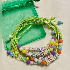 a green bag with some beads and letters on it next to a necklace that says happy birthday