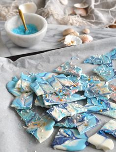 blue and white pieces of glass sitting on top of a piece of paper next to a bowl