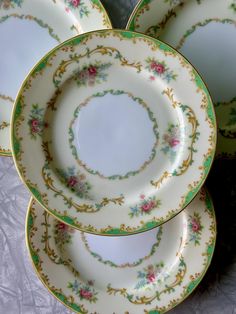 four plates are stacked on top of each other with floral designs and gold trimmings