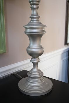 a silver candle holder sitting on top of a black table next to a mirror and door