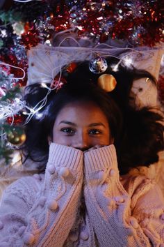 a woman covers her face in front of a christmas tree