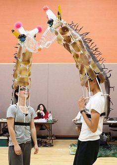 two young men standing next to each other in front of a giraffe sculpture