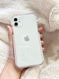 a woman holding an iphone case in her hand on top of a white fluffy blanket