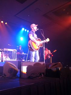 a man standing on top of a stage holding a guitar