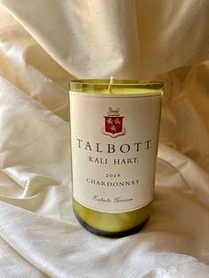 a bottle of wine sitting on top of a white cloth covered tablecloth next to a candle