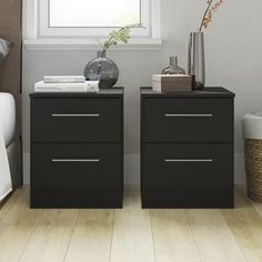 two nightstands side by side in a bedroom with white walls and wood floors, one has a vase on top