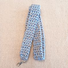 a crocheted blue and white scarf laying on top of a beige carpet next to a pair of scissors