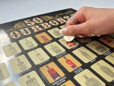 a person's hand on top of a 50 - ounce coin with labels for various liquors