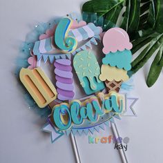 a cake topper with ice cream and cupcakes on it next to some leaves