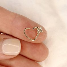 a woman's hand with a gold heart shaped ring on her thumb and a white manicure