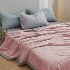 a bed with pink sheets and blue pillows