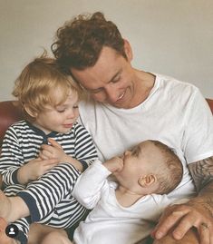 a man sitting on top of a couch holding a baby