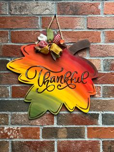 a colorful sign hanging on the side of a brick wall that says, happy thanksgiving