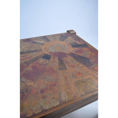 a wooden table with an artistic design painted on the top and bottom part, in front of a blue sky