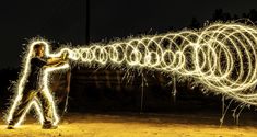 a man standing in front of a long string of lights with his hands on the strings