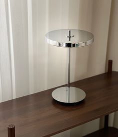 a table with a mirror on top of it and a lamp in the corner next to it