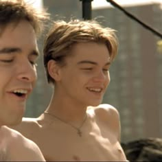 two shirtless young men standing next to each other in front of a street light