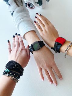 three people wearing bracelets and rings on their hands, with one holding the other's hand