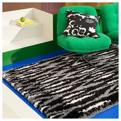 a green chair sitting on top of a black and white rug