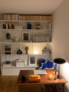 a desk with a laptop computer on top of it next to a bookshelf