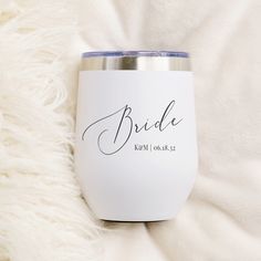 a white wine glass with the word bride printed on it sitting on a fluffy blanket