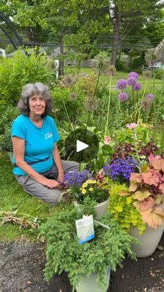 an older woman sitting on the ground next to potted plants in a garden area