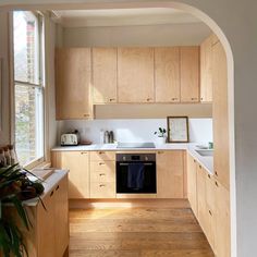 a kitchen with wooden cabinets and white counter tops is seen through an arch in the wall