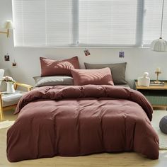 a bed in a bedroom with red sheets and pillows