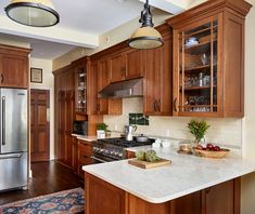 a kitchen with wooden cabinets and marble counter tops, along with an island in the middle