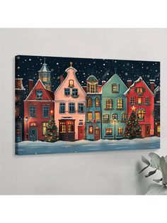 a christmas scene with houses and trees in the snow on a white wall next to a potted plant