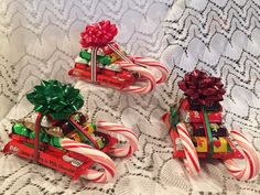 three small candy canes with bows on them sitting on a white lace tablecloth