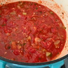 a large pot filled with lots of red sauce on top of a blue stovetop