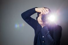 a man taking a photo with his camera in front of the light coming from behind him