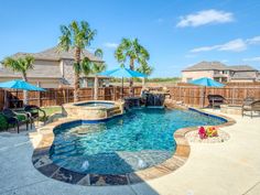 a backyard with a pool and hot tub surrounded by palm trees